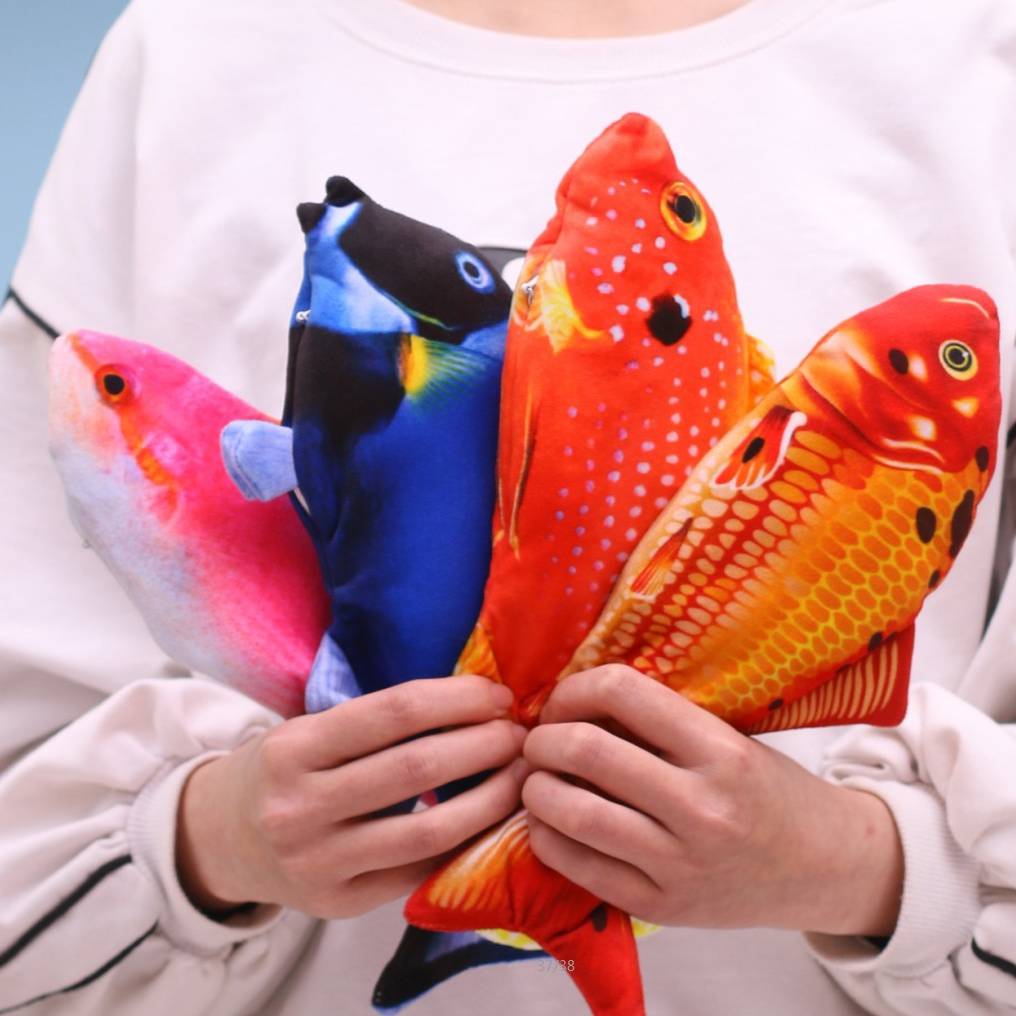 Varios peces KickFish de peluche sujetos con las manos para mostrar su tamaño real