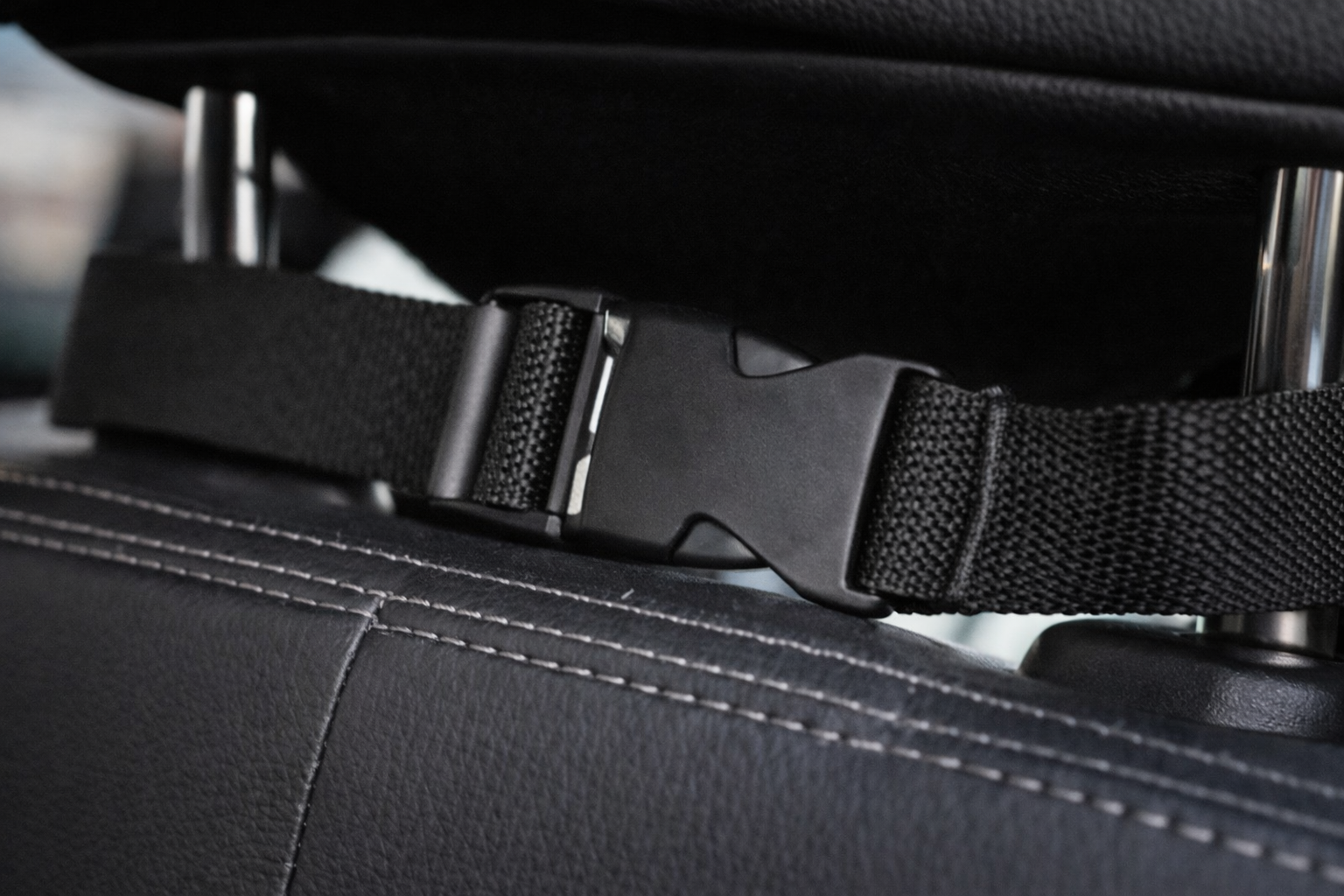 Detalle de la correa y hebilla de fijación al reposacabezas del protector de asiento para coche